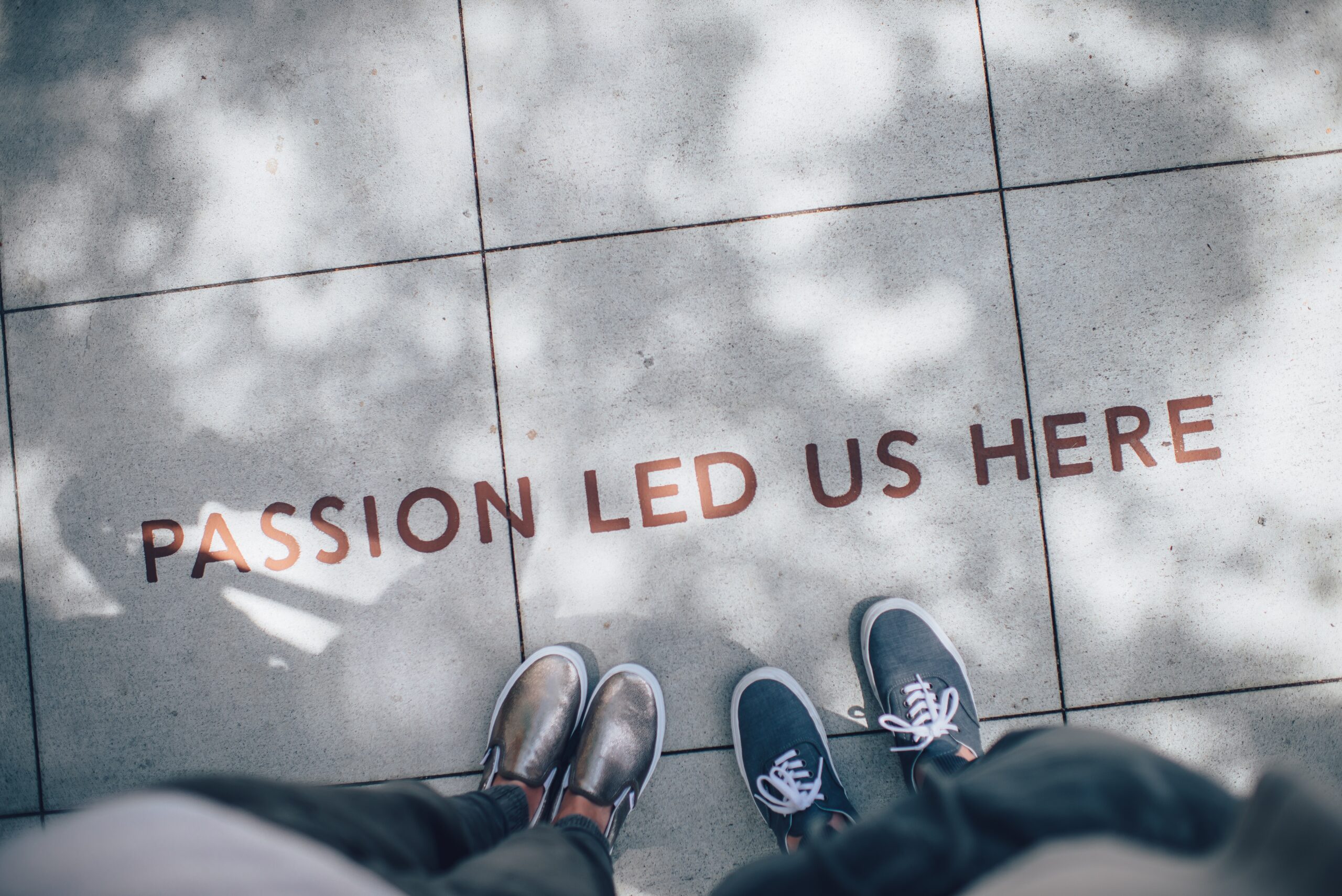 Feet on sidewalk with words, "Passion Led Us Here"